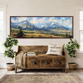 a large wooden bench with a "welcome home" pillow, surrounded by potted plants and a large landscape painting hanging on the wall above it.