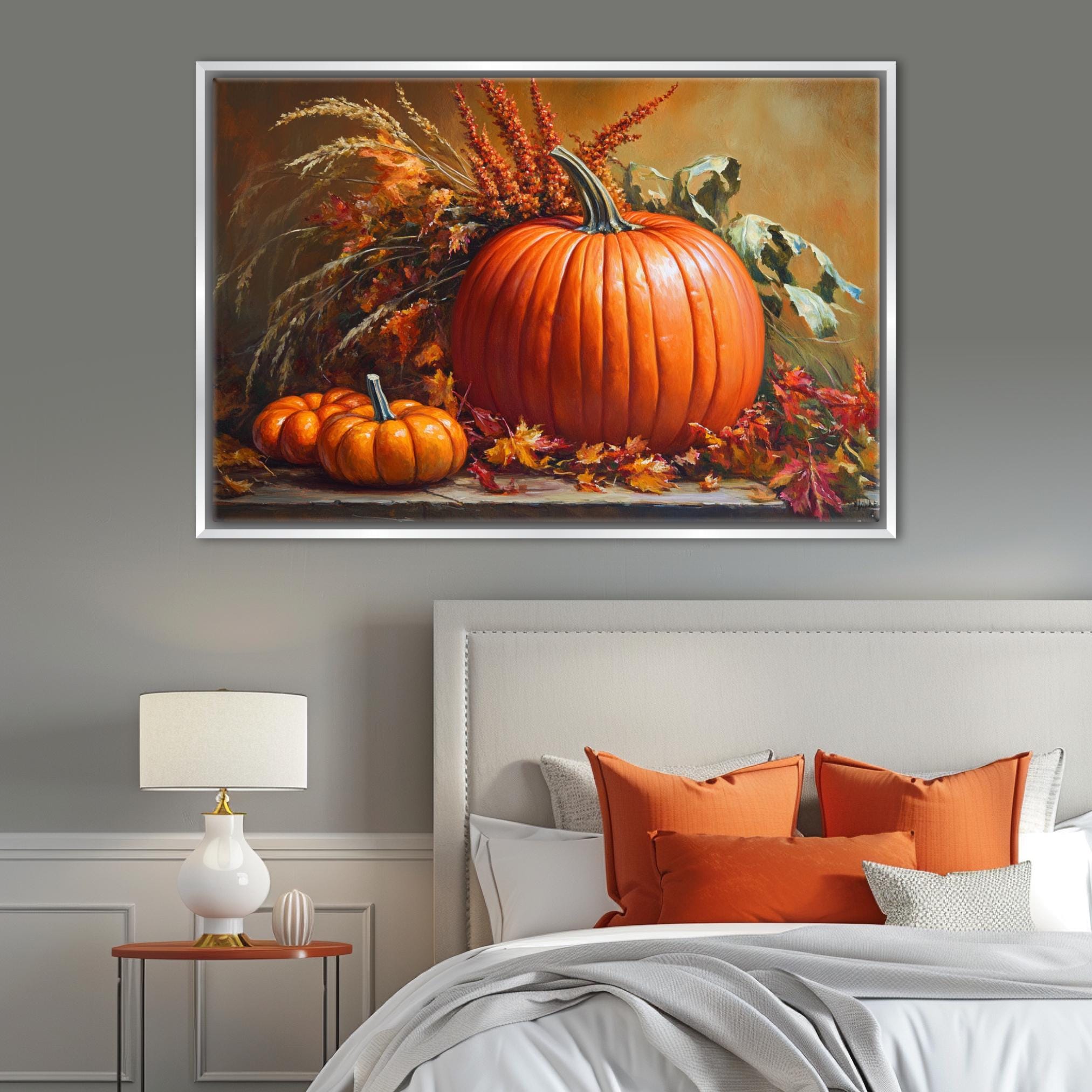 a large framed painting of a pumpkin and other fall-themed decorations hanging on a wall above a bed with orange pillows and a white headboard.
