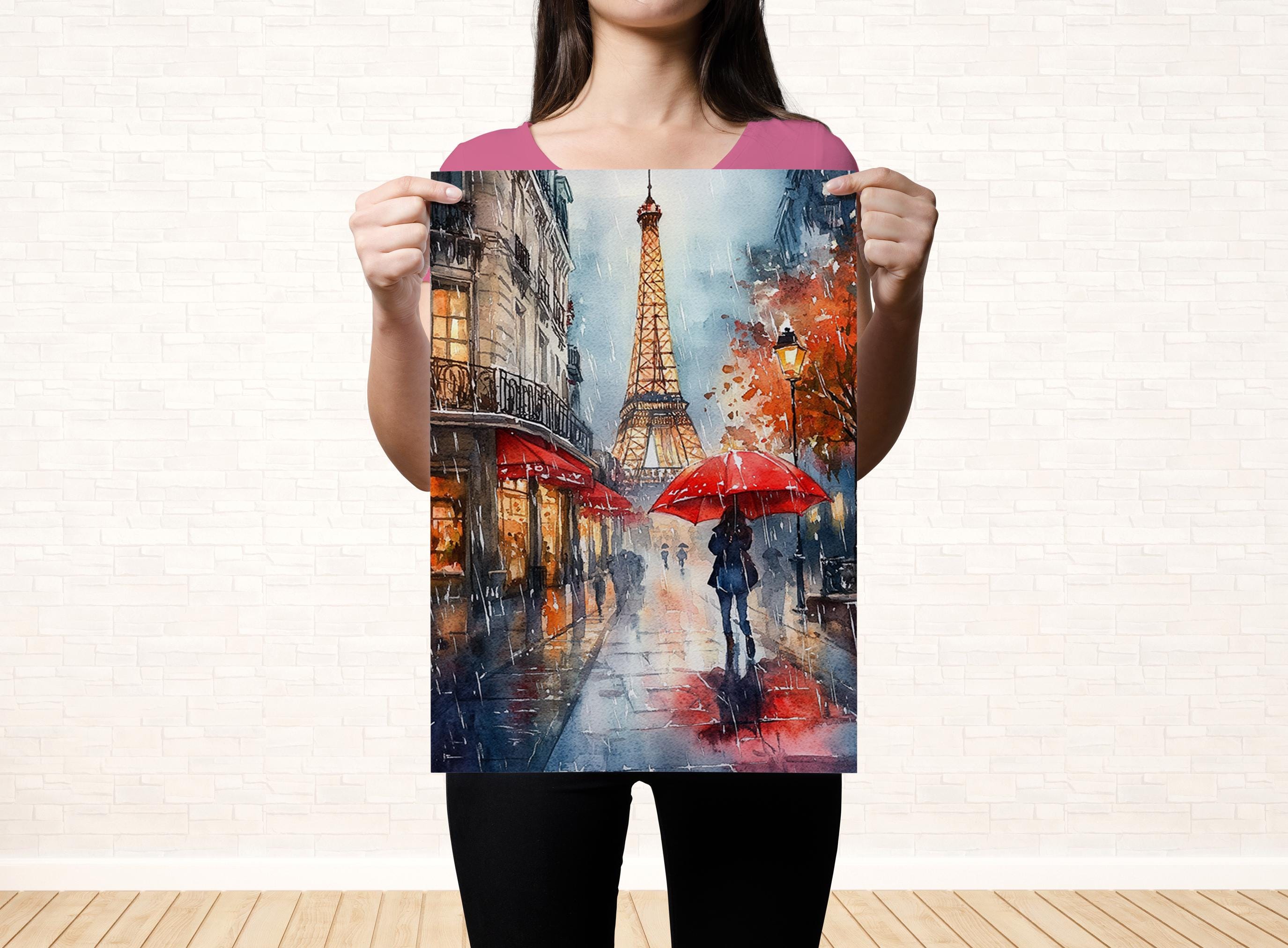 A woman holds up a framed painting depicting a rainy scene with the Eiffel Tower in the background.