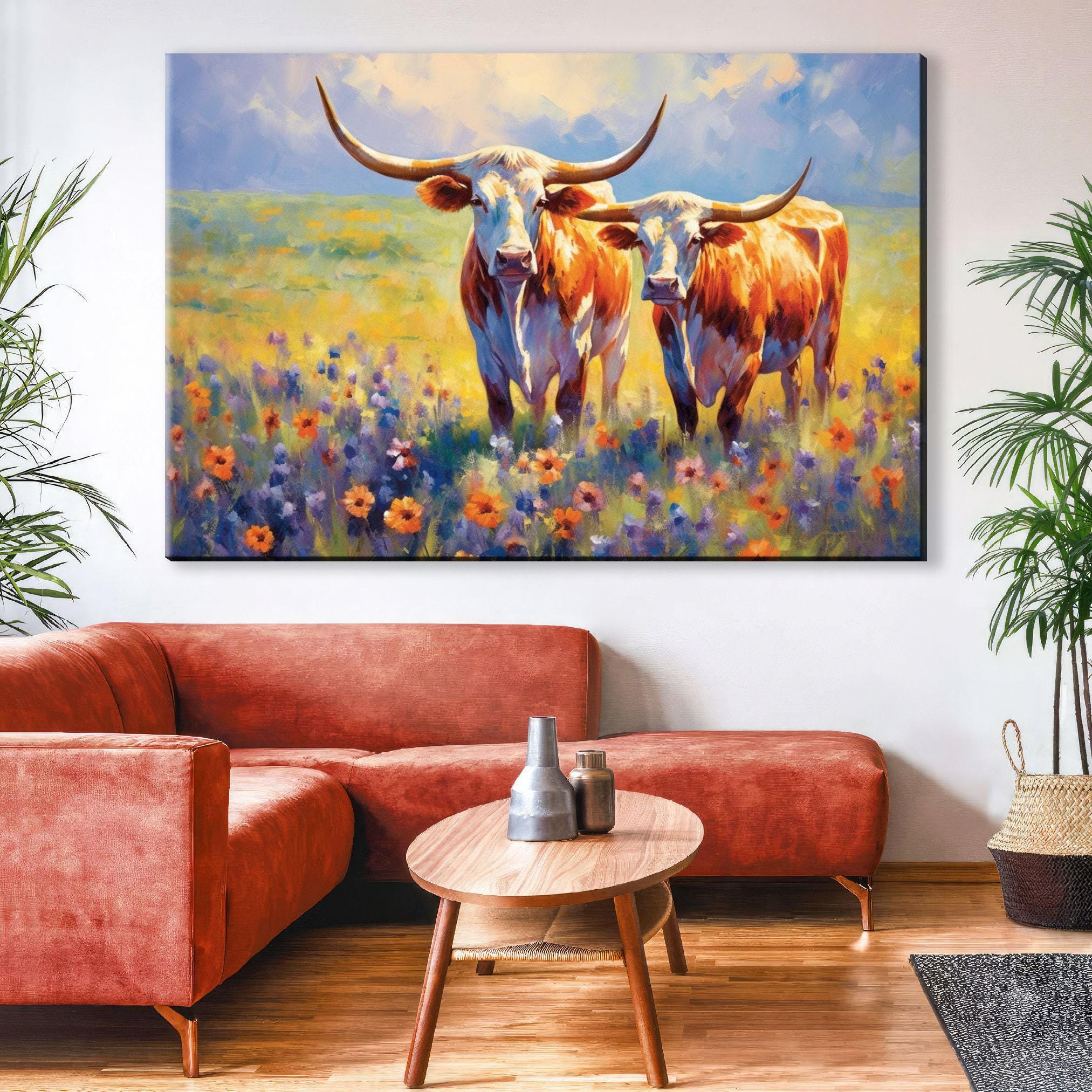 a large painting of two cows standing in a field of flowers, with a wooden table in the foreground.