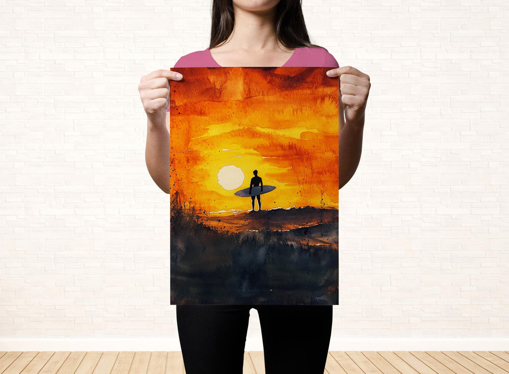 A woman holds up a framed painting depicting a surfer on a beach at sunset.