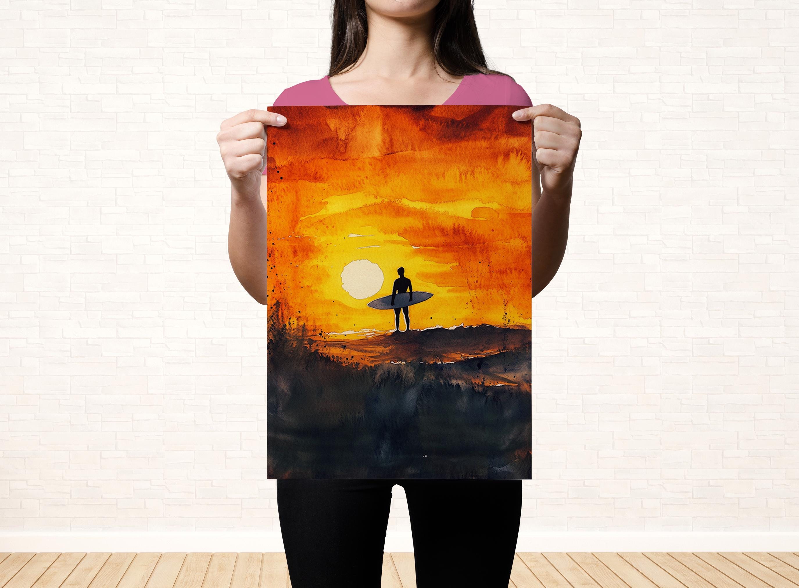 A woman holds up a framed painting depicting a surfer on a beach at sunset.