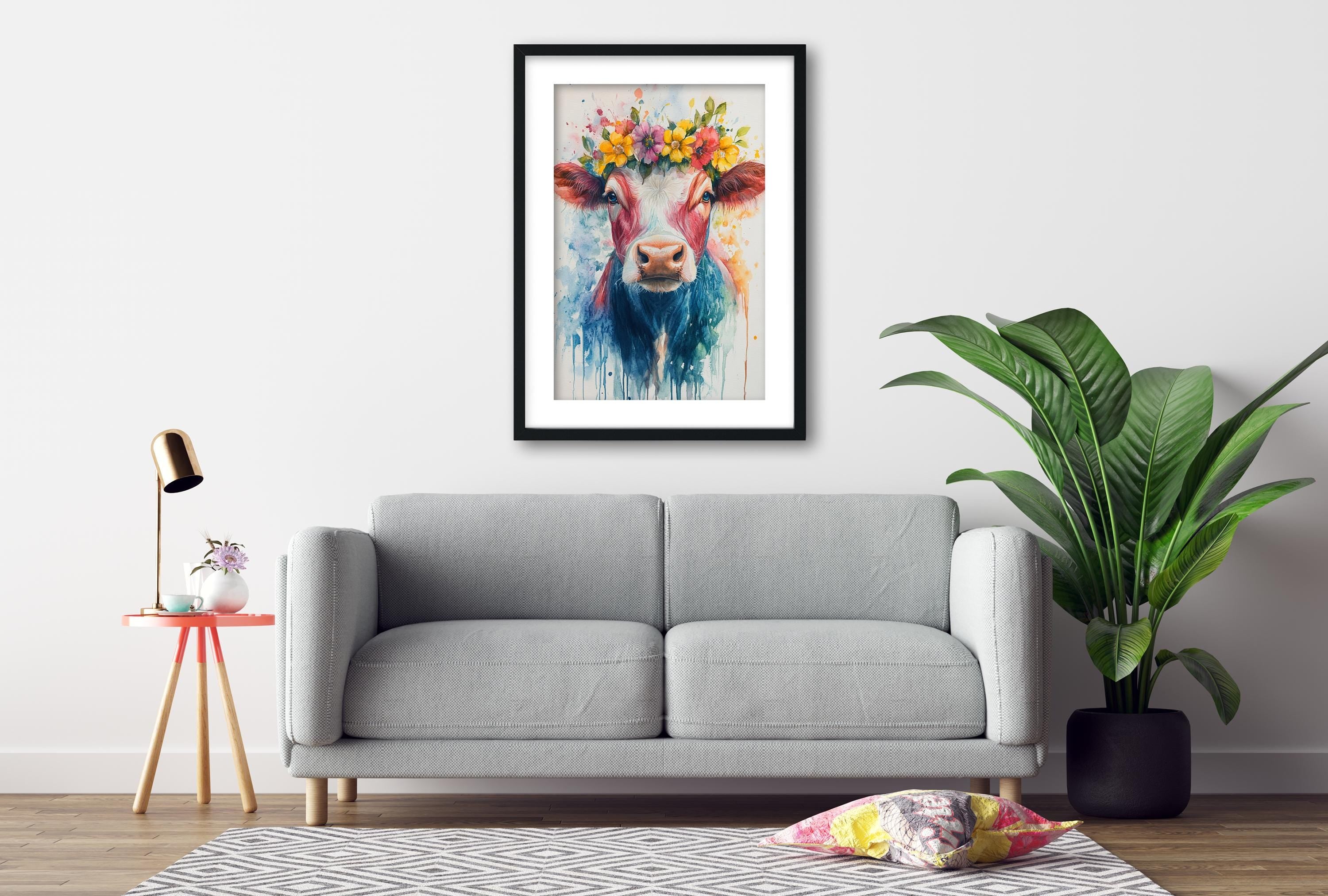 a gray sofa, a framed painting of a cow with a colorful flower crown, a small table with a lamp, and a potted plant, all arranged in a cozy living room setting.