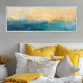 a bed with yellow and white pillows and a painting on the wall