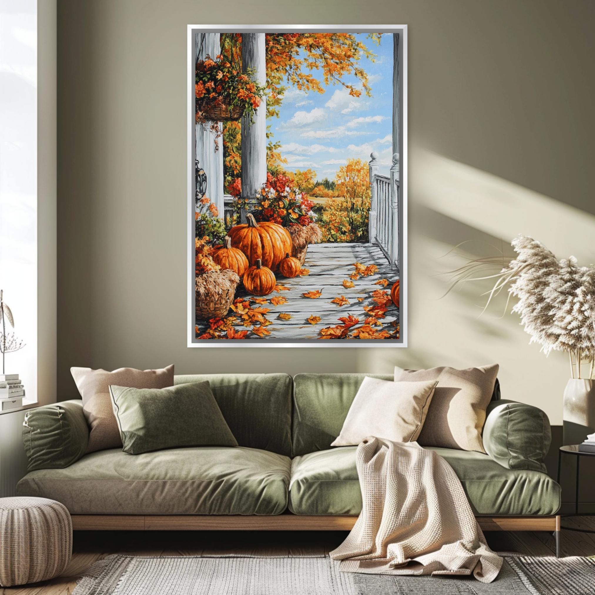 a large framed painting of a porch with pumpkins and autumn leaves, hanging on a wall above a green couch in a living room setting.