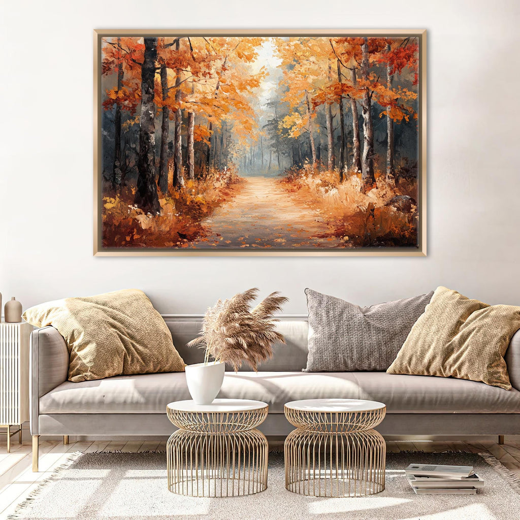 a large painting of a forest path with autumn trees, hanging on a wall above a gray sofa with two round coffee tables in front of it.