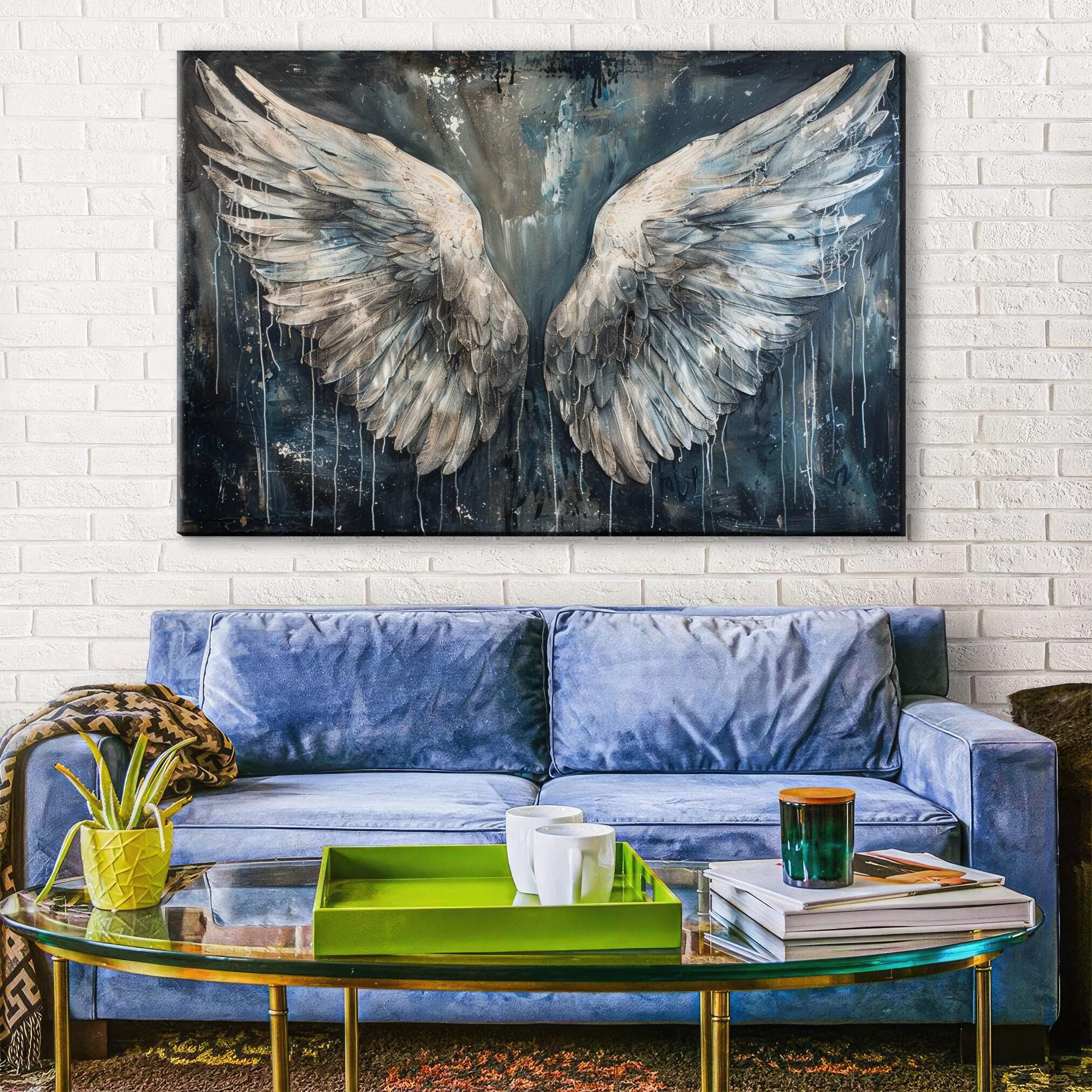 a large painting of white and gray wings hanging on a white brick wall above a blue couch in a living room setting.